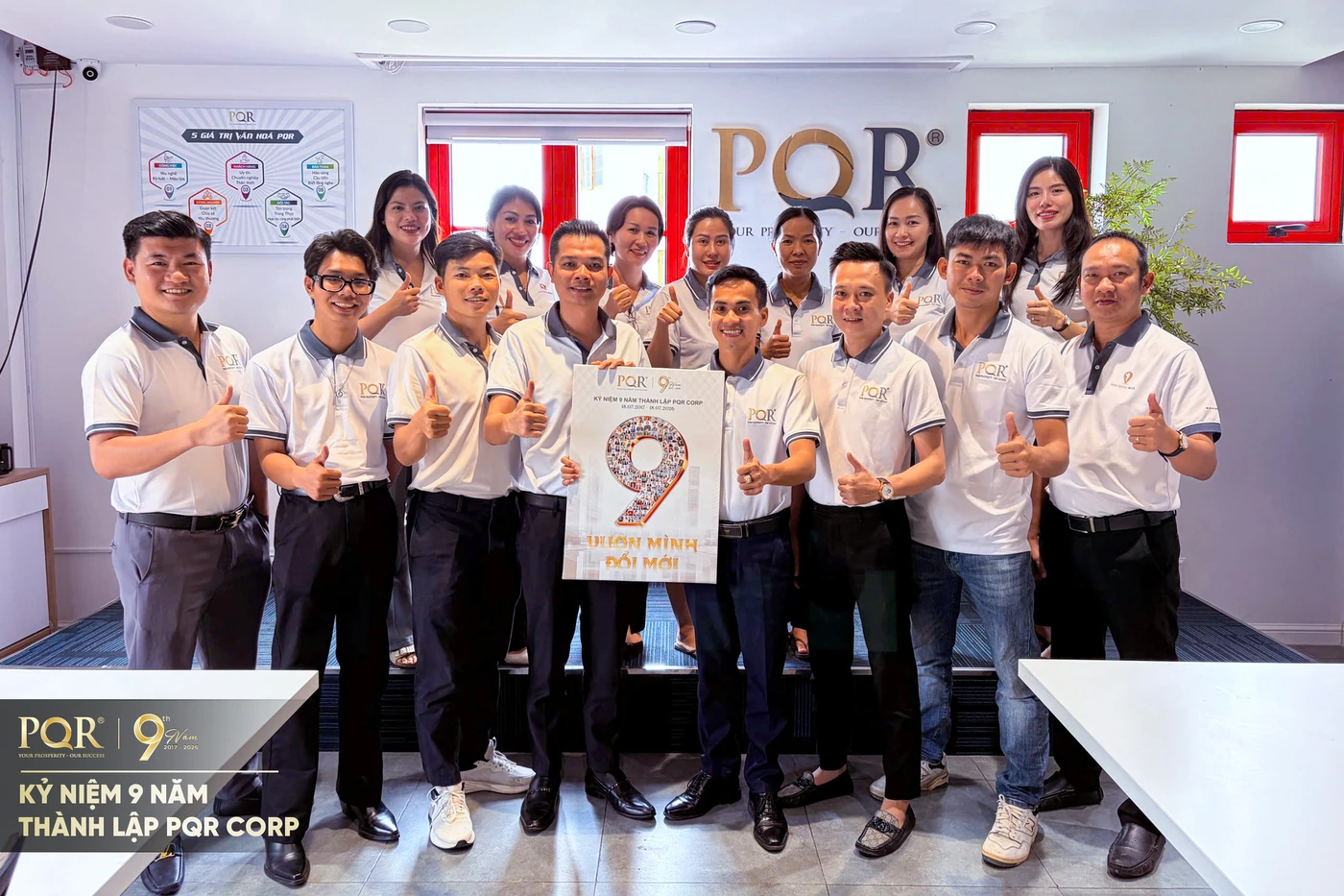 Một phòng ban PQR chụp ảnh lưu niệm cùng standee kỷ niệm 9 năm thành lập công ty.